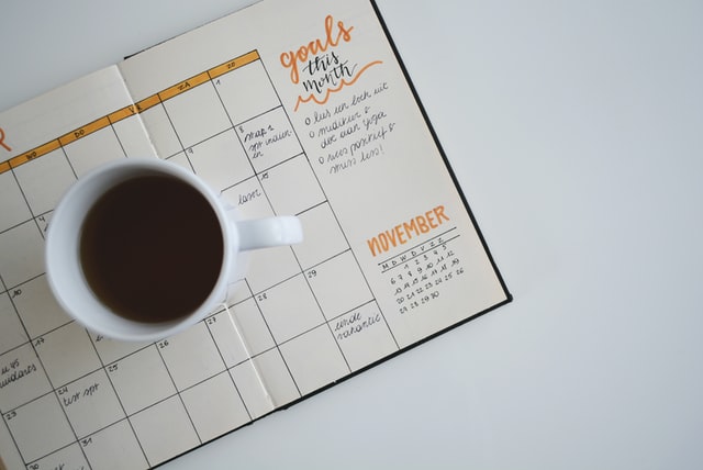 スケジュール帳とコーヒーの画像